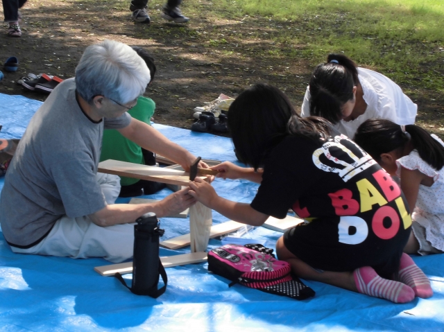 校庭の木陰で親子で作品づくりに取り組む様子